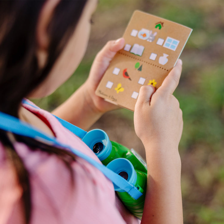 A kid playing with The Melissa & Doug Let's Explore Binoculars & Compass Play Set