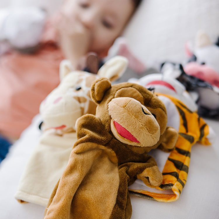 A kid playing with The Melissa & Doug Animal Hand Puppets 2-Pack (4 animals in each) - Zoo Friends and Farm Friends