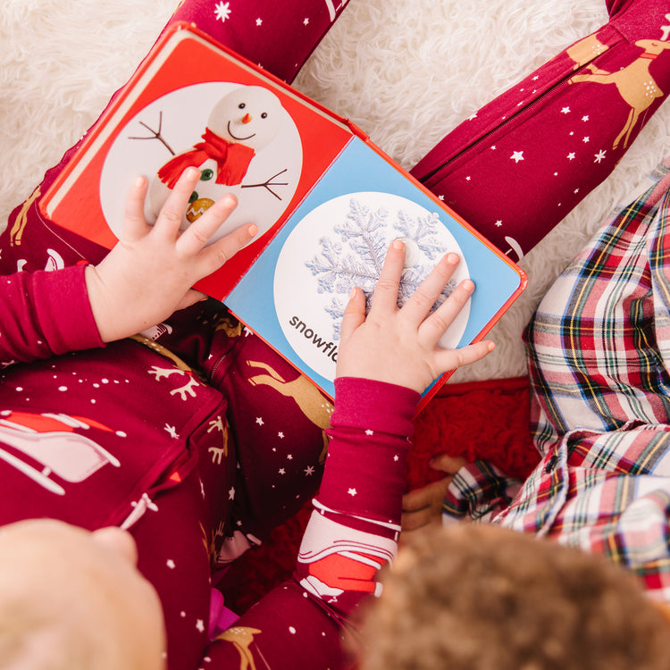 A kid playing with The Melissa & Doug Children’s Book – Poke-a-Dot: Christmas (Board Book with Buttons to Pop)