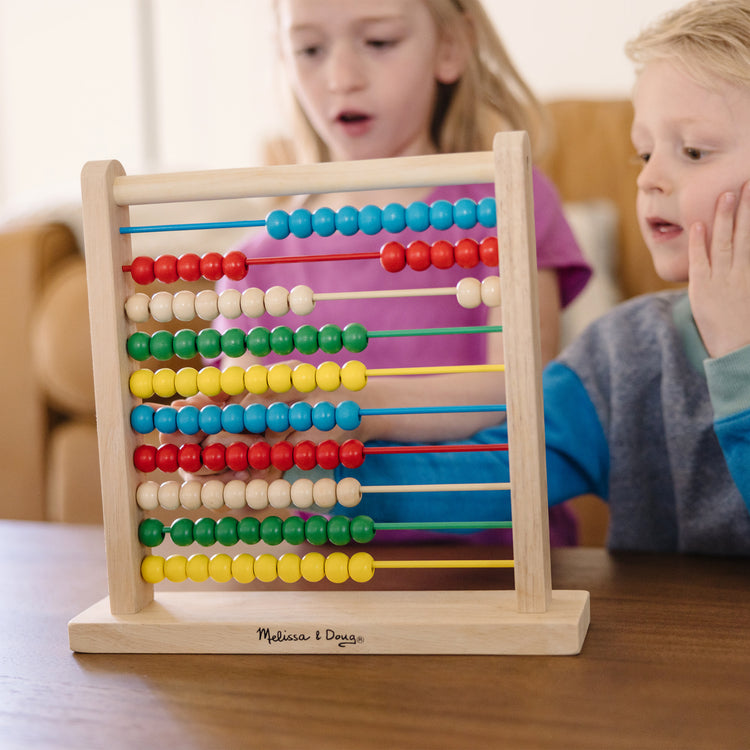 A kid playing with The Melissa & Doug Abacus - Classic Wooden Educational Counting Toy With 100 Beads