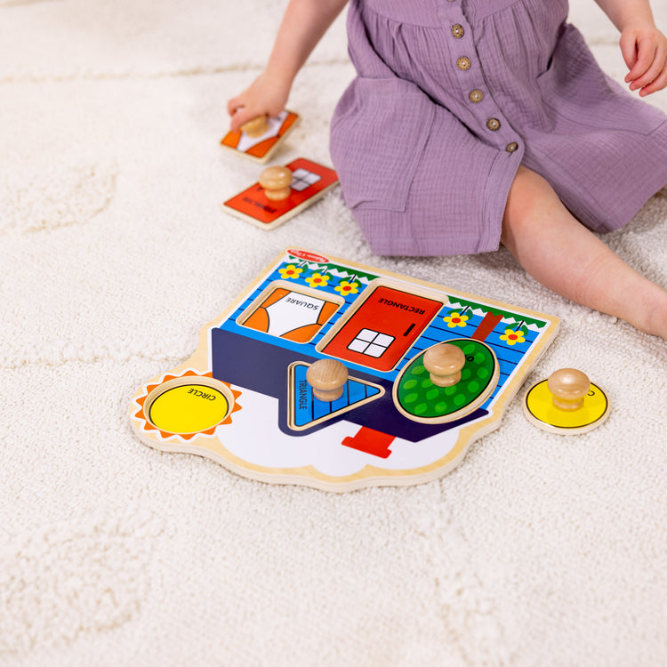 A kid playing with The Melissa & Doug First Shapes Jumbo Peg Wooden Puzzle