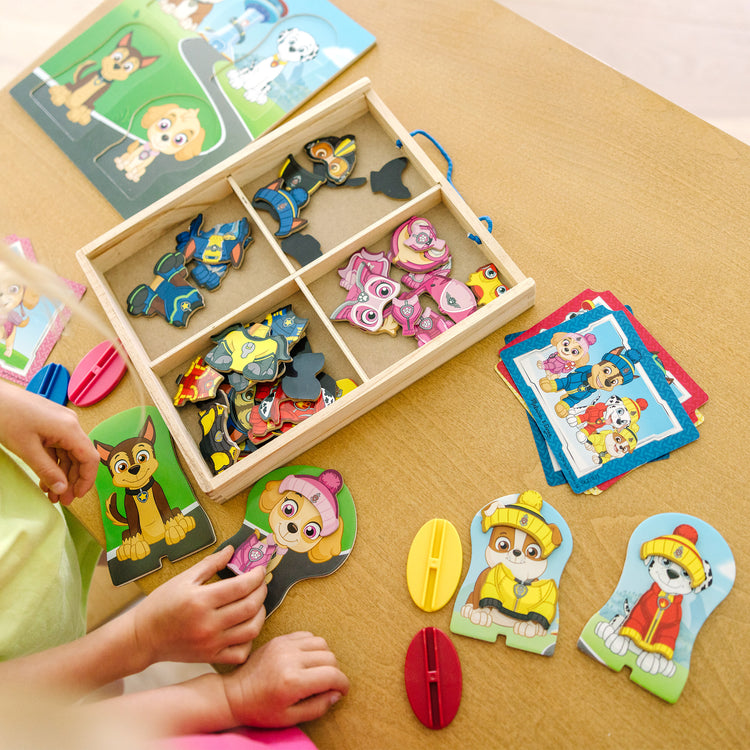 A kid playing with The Melissa & Doug PAW Patrol Wooden Magnetic Pretend Play (64 Pieces), Multi color