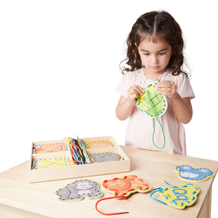 A kid playing with The Melissa & Doug Alphabet Wooden Lacing Cards With Double-Sided Panels and Matching Laces