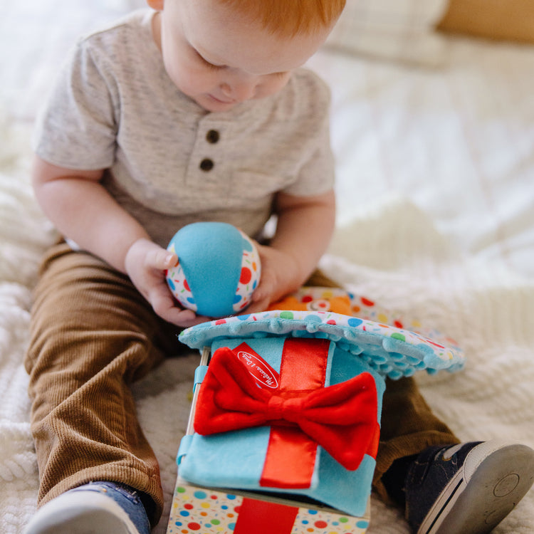 A kid playing with The Melissa & Doug Wooden Surprise Gift Box Infant Toy (5 Pieces)