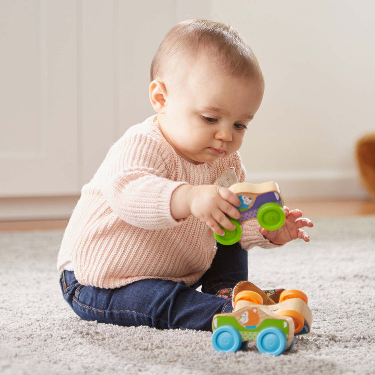 A kid playing with The Melissa & Doug First Play Wooden Animal Stacking Cars (3 pcs)