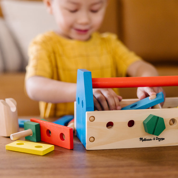 A kid playing with The Melissa & Doug Take-Along Tool Kit Wooden Construction Toy (24 pcs)