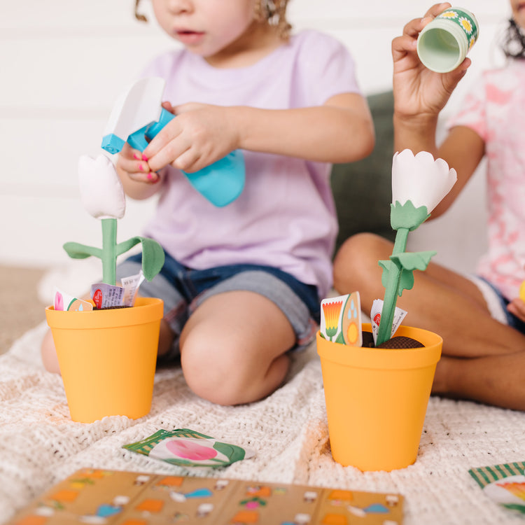 A kid playing with The Melissa & Doug Let’s Explore Flower Gardening Play Set with Color-Changing Flowers (16 Pieces)