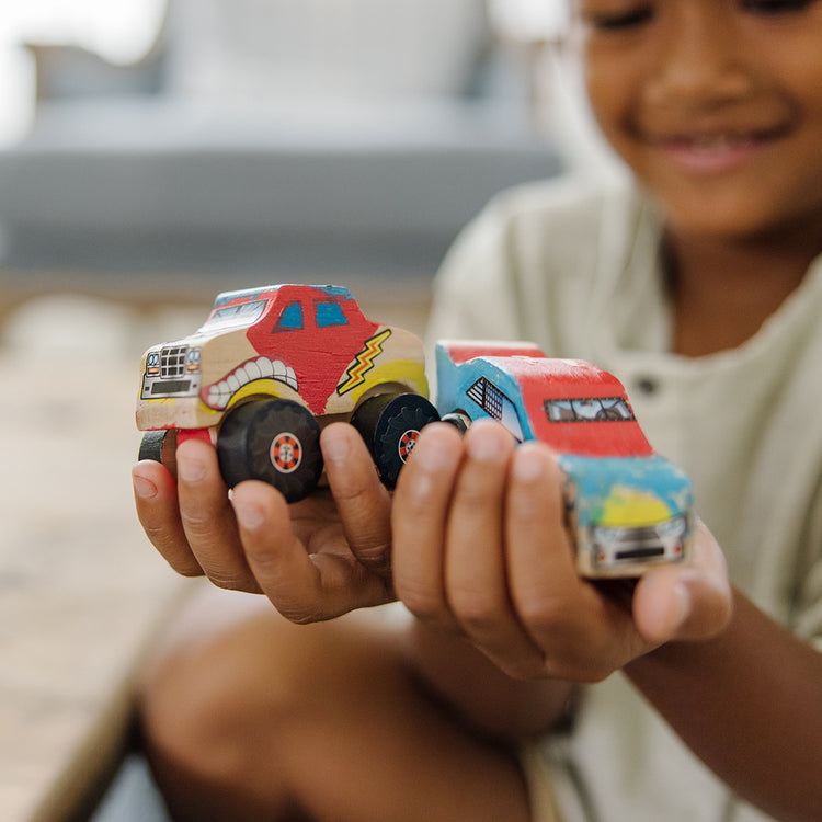 A kid playing with The Melissa & Doug Decorate-Your-Own Wooden Craft Kits Set - Race Car and Monster Truck