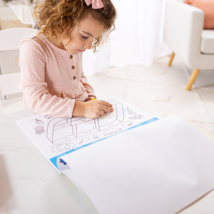 A kid playing with The Melissa & Doug Playmats Food Fun Take-Along Paper Coloring And Learning Activity Pads (24 Pages)