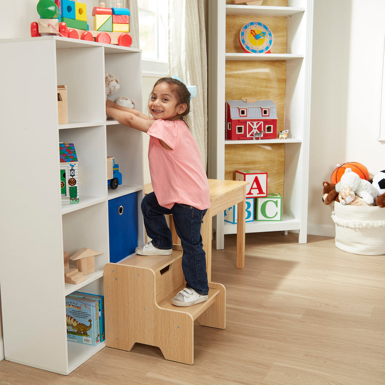 A kid playing with The Melissa & Doug Kids Wooden Step Stool - Light Natural Finish