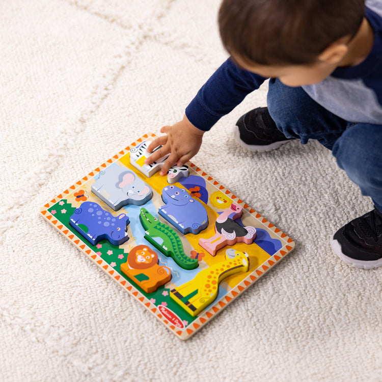 A kid playing with The Melissa & Doug Safari Wooden Chunky Puzzle - 8 Pieces