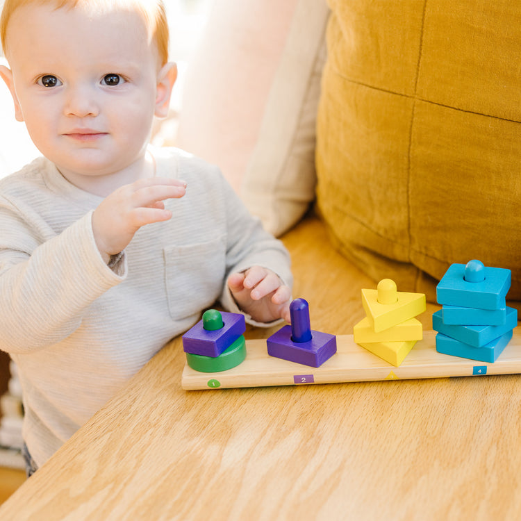 A kid playing with The Melissa & Doug Stack and Sort Board - Wooden Educational Toy With 15 Solid Wood Pieces