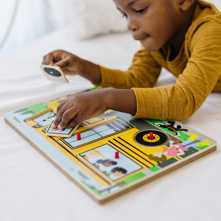 A kid playing with The Melissa & Doug The Wheels on the Bus Sound Puzzle