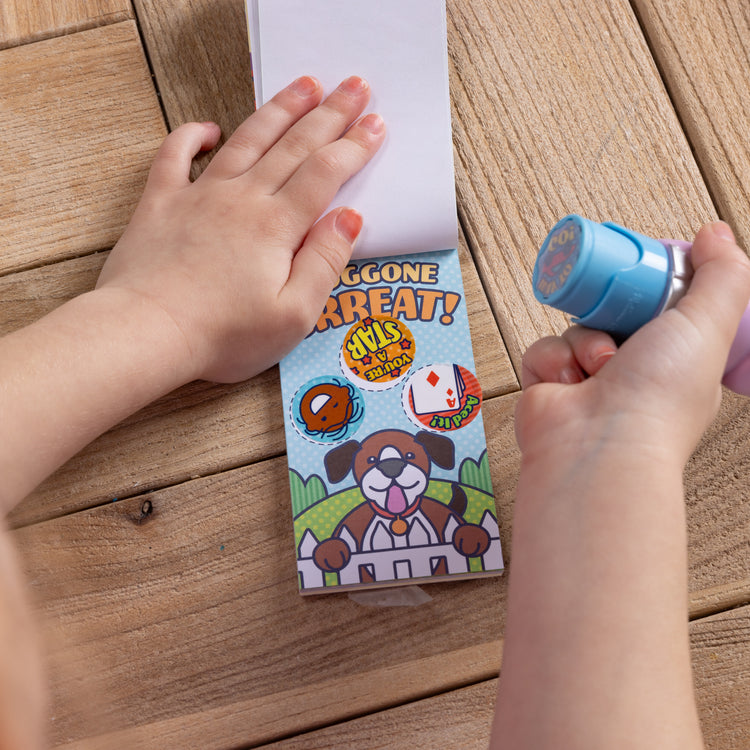 A kid playing with The Melissa & Doug Sticker WOW!™ Mini Activity Pad and 200+ Refill Stickers for Sticker Stamper Arts and Crafts Fidget Toy Collectibles – Assorted Way to Go! Reward Stickers