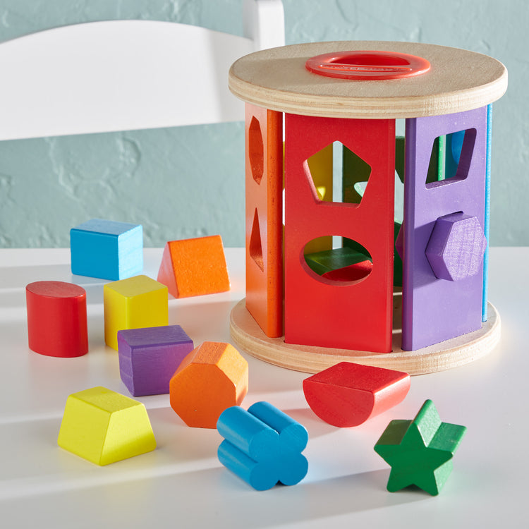 A playroom scene with The Melissa & Doug Match and Roll Shape Sorter - Classic Wooden Toy