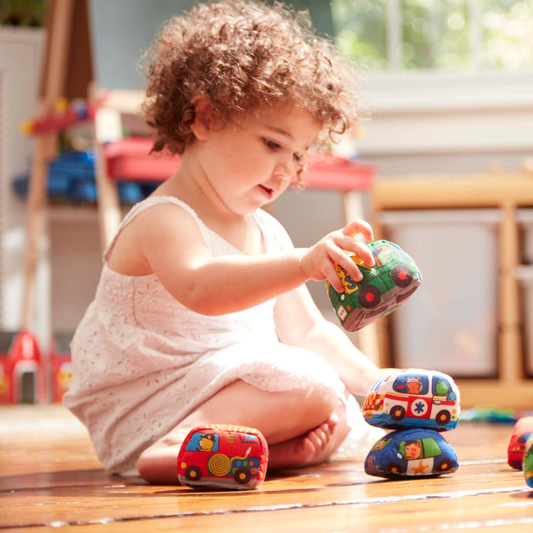 A kid playing with The Melissa & Doug Take-Along Town Play Mat (19.25 x 14.25 inches) With 9 Soft Vehicles