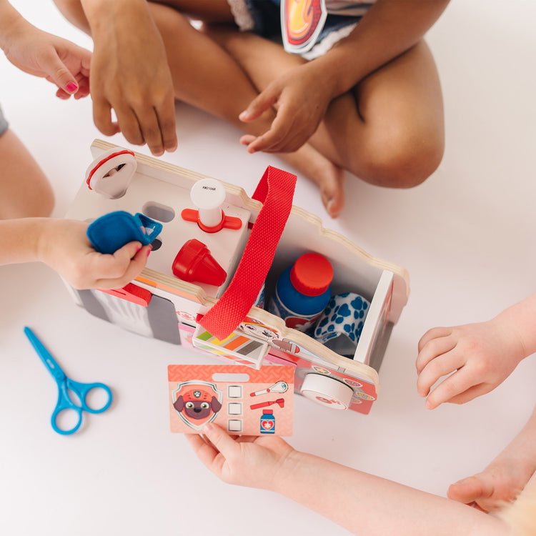 A kid playing with The Melissa & Doug PAW Patrol Marshall's Wooden Rescue EMT Caddy (14 Pieces)