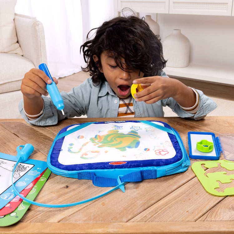 A kid playing with The Melissa & Doug Water WOW! Water WOW! Take-Along Multi-Activity Color-Reveal Drawing Set Travel Toy Ages 3+