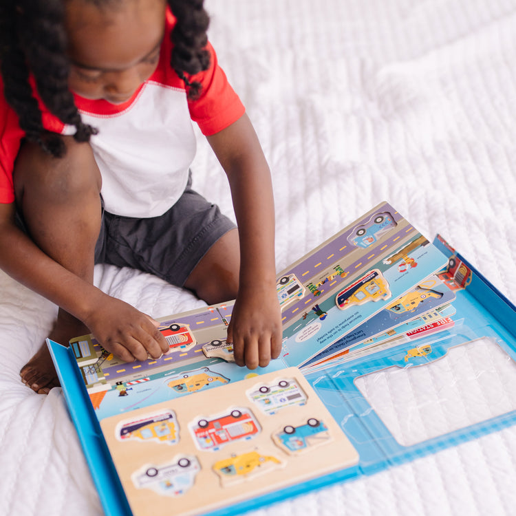 A kid playing with The Melissa & Doug To the Rescue Book and Wooden 6-Piece Puzzle Play Set