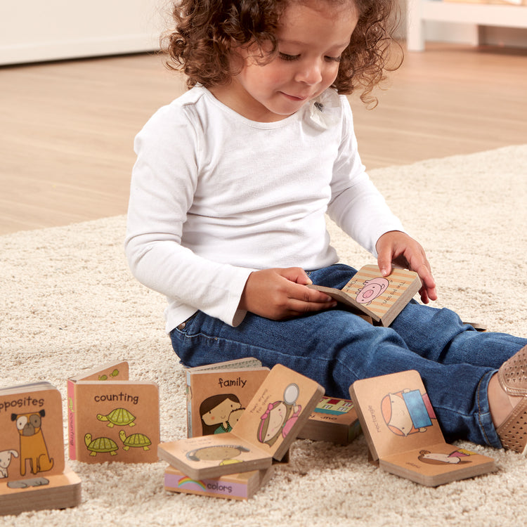 A kid playing with The Melissa & Doug Children's Book - Natural Play Book Tower: Little Learning Books