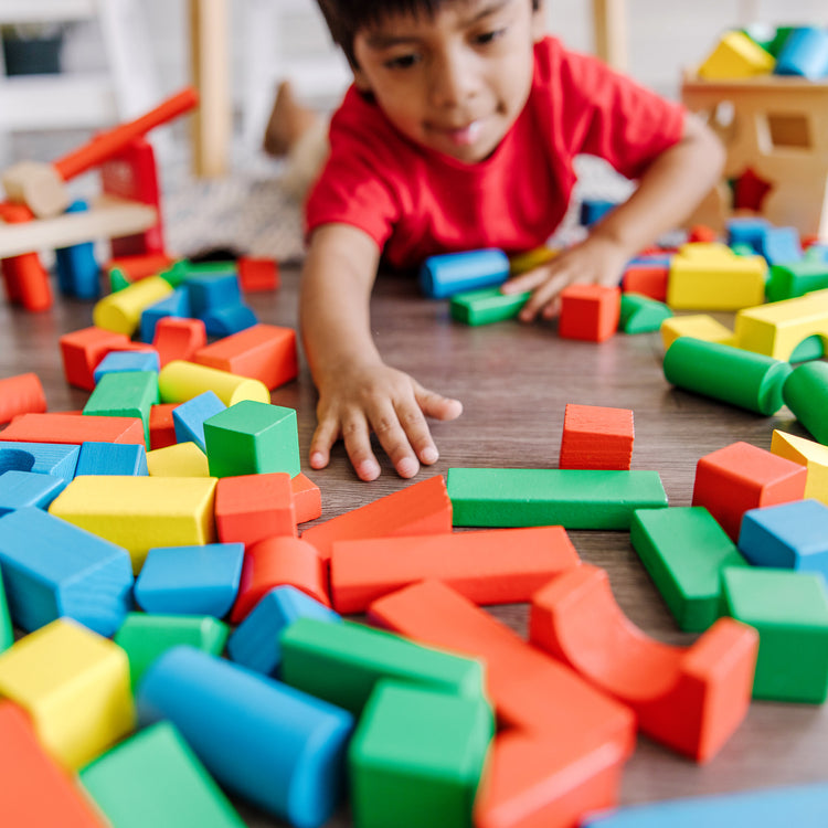 A kid playing with The Melissa & Doug Stack, Sort & Pound Wooden Toy Collection (Building Blocks, Shape Sorter, Pounding Bench)