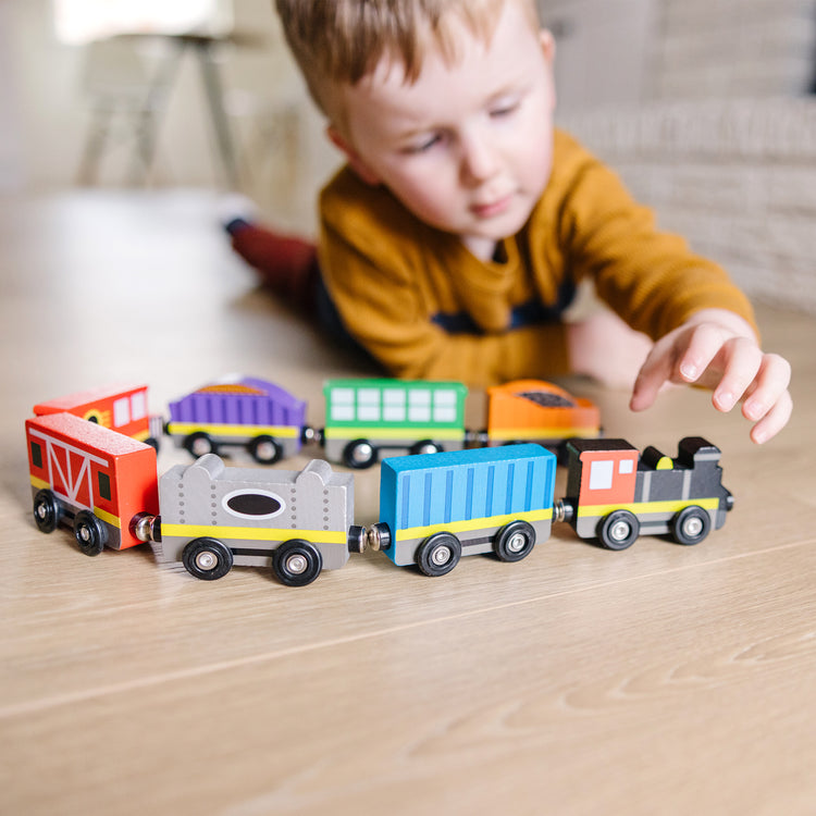 A kid playing with The Melissa & Doug Wooden Magnetic Train Cars - 8 Piece Educational and Skill-Building Wooden Toy for Boys and Girls