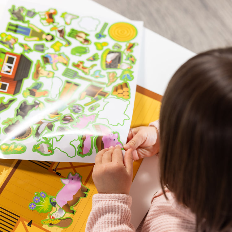 A kid playing with The Melissa & Doug Reusable Sticker Pad: Farm - 280+ Stickers, 5 Scenes