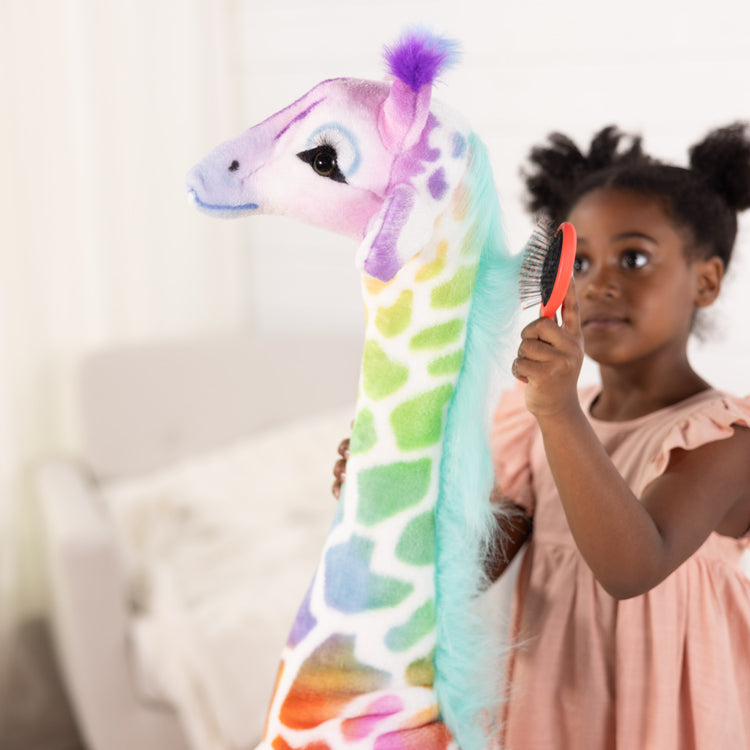 A kid playing with The Melissa & Doug Rainbow Giraffe Lifelike Plush
