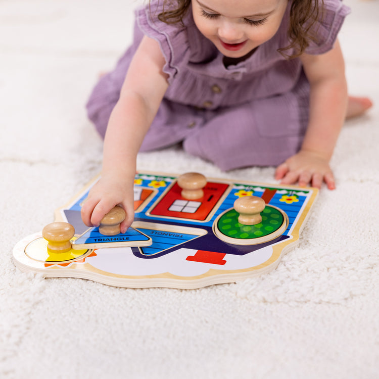 A kid playing with The Melissa & Doug First Shapes Jumbo Peg Wooden Puzzle