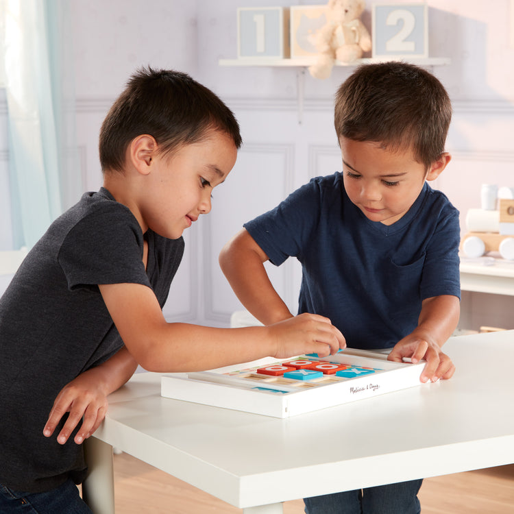 A kid playing with The Melissa & Doug Wooden Tic-Tac-Toe Board Game with 10 Self-Storing Wooden Game Pieces (12.5” W x 8.5” L x 1.25” D)