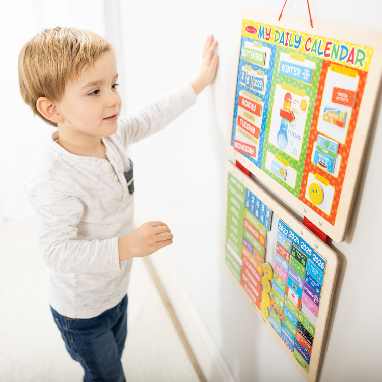 A kid playing with The Melissa & Doug My First Daily Magnetic Calendar