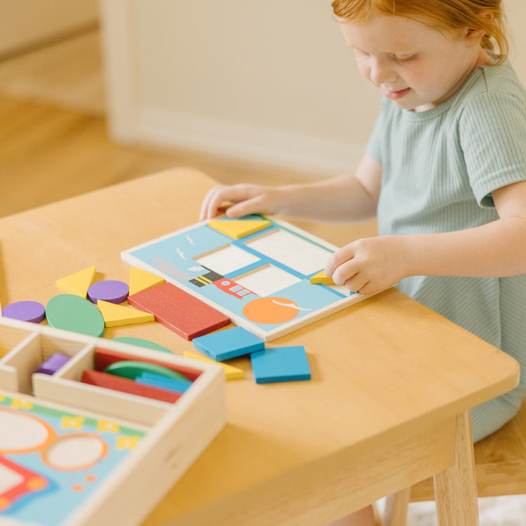 A kid playing with The Melissa & Doug Beginner Wooden Pattern Blocks Educational Toy With 5 Double-Sided Scenes and 30 Shapes
