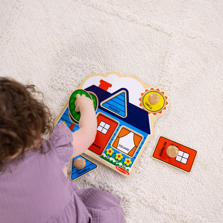 A kid playing with The Melissa & Doug First Shapes Jumbo Peg Wooden Puzzle