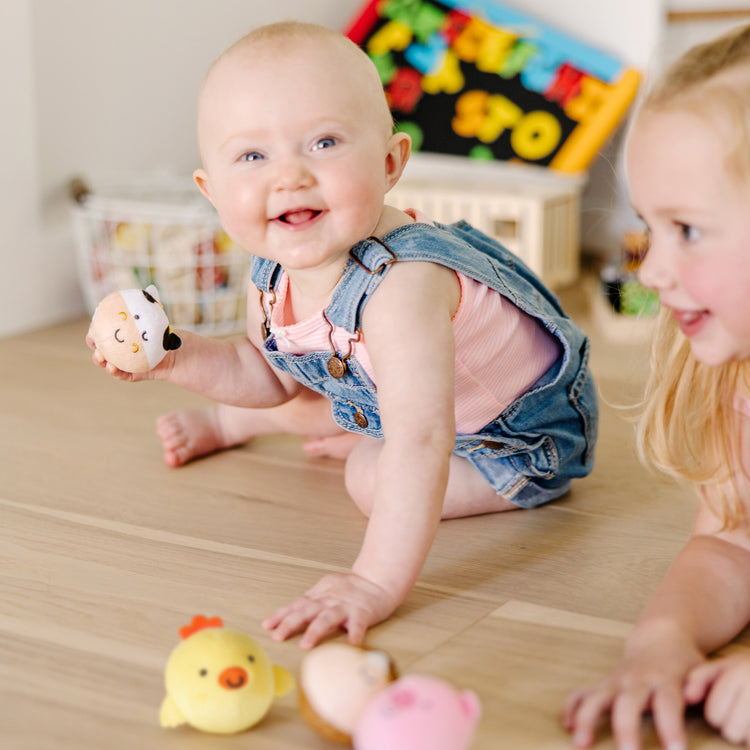 A kid playing with The Melissa & Doug Rollables Farm Friends Infant and Toddler Toy (4 Pieces)