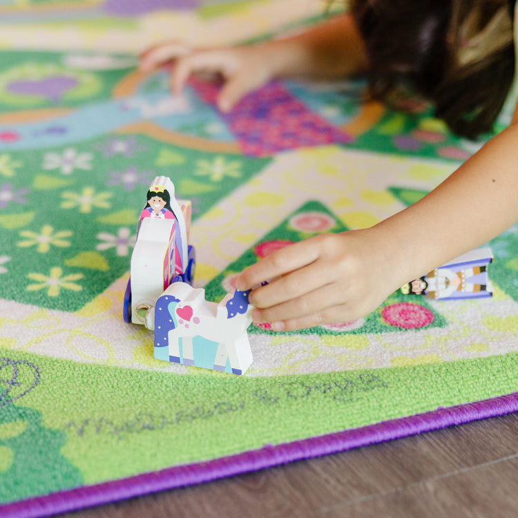 A kid playing with The Melissa & Doug Magical Kingdom Activity Rug Play Set – 4 Wooden Play Pieces