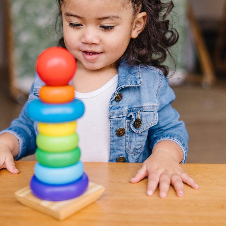 A kid playing with The Melissa & Doug Rainbow Stacker Wooden Ring Educational Toy