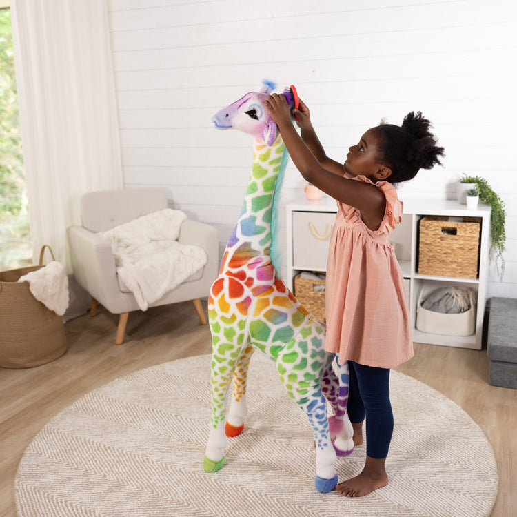 A kid playing with The Rainbow Giraffe Lifelike Plush