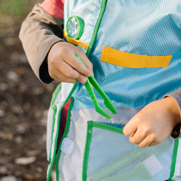 A kid playing with The Melissa & Doug Let’s Explore Naturalist Vest Play Set – 20 Pieces