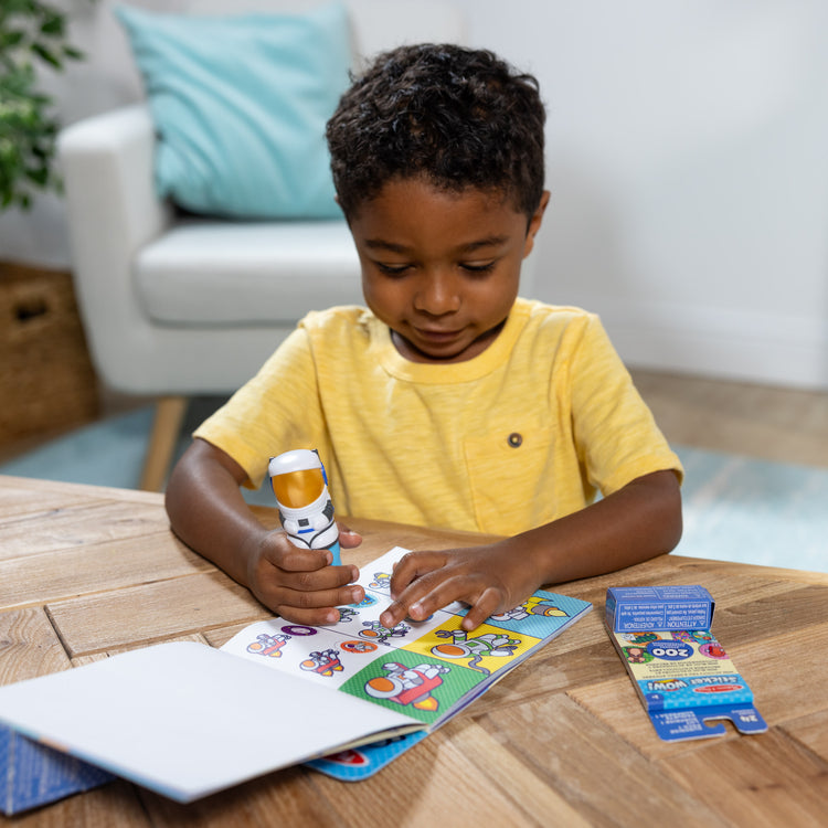 A kid playing with The Melissa & Doug Sticker WOW!™ Astronaut Bundle: 24-Page Activity Pad, Sticker Stamper, Mini Activity Pad, 500 Stickers, Arts and Crafts Fidget Toy Collectible Character