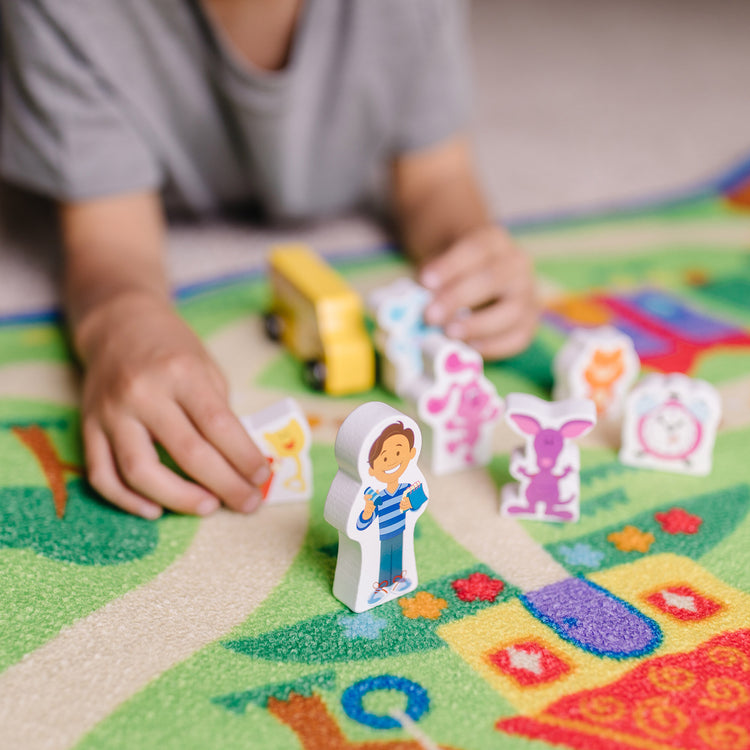 A kid playing with The Melissa & Doug Blue's Clues & You! Blue's Neighborhood Activity Rug (44 Inches x 26 Inches Rug, 9 Wooden Play Pieces)