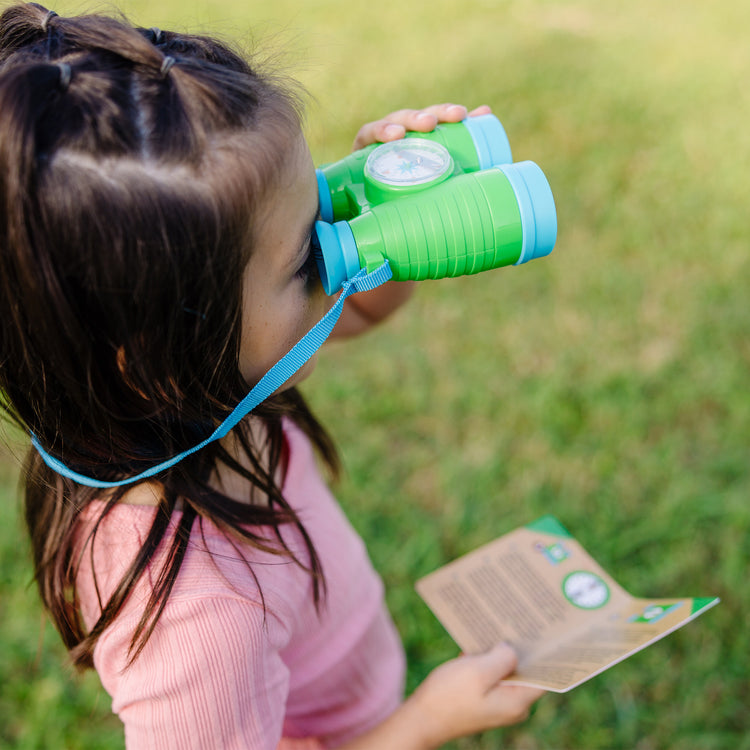 A kid playing with The Melissa & Doug Let's Explore Binoculars & Compass Play Set