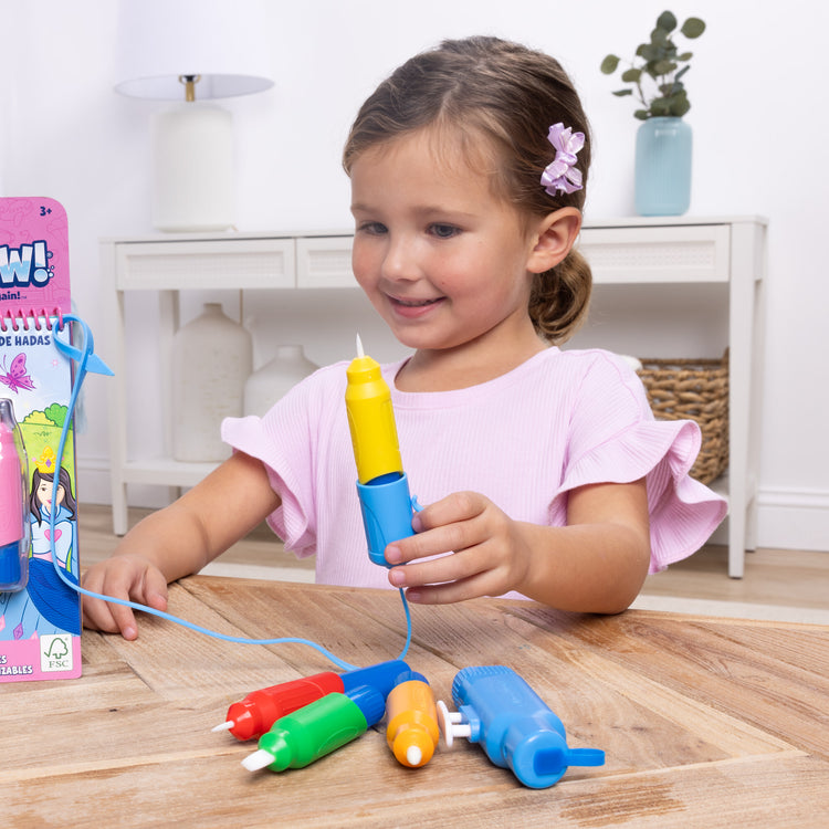 A kid playing with The Melissa & Doug Water WOW! Pen Pack - 4 Color-with-Water Pens, Sprayer, Tether Cap