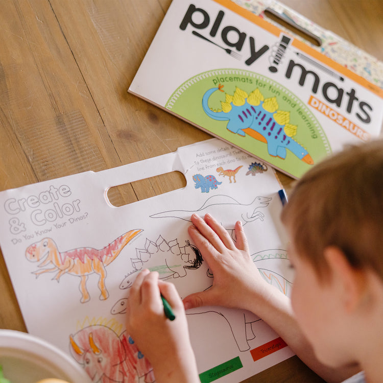 A kid playing with The Melissa & Doug Playmats Dinosaurs Take-Along Paper Coloring And Learning Activity Pads (24 Pages)