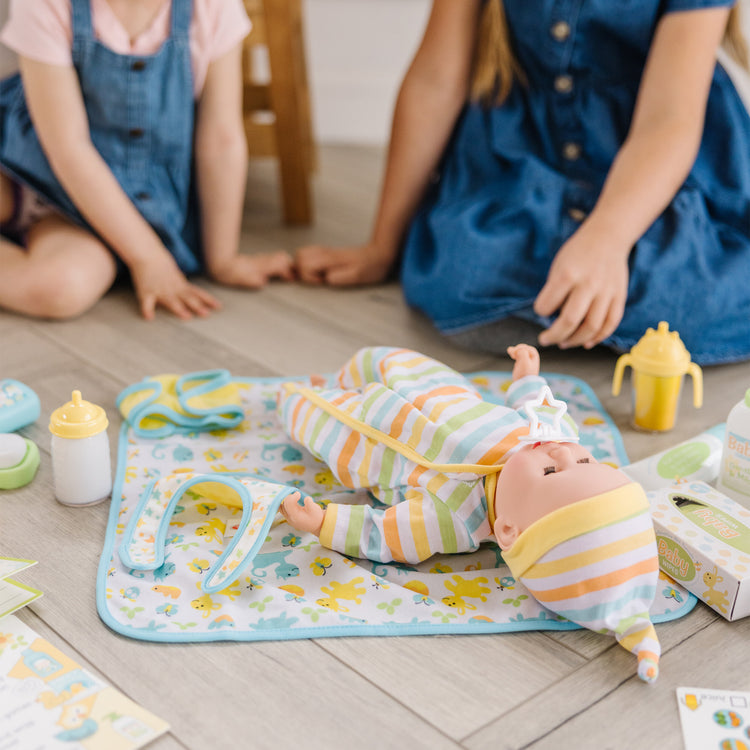 A kid playing with The Melissa & Doug Mine to Love Deluxe Baby Care Play Set (48 Pieces – Doll + Accessories to Feed, Bathe, Change, and Cuddle)