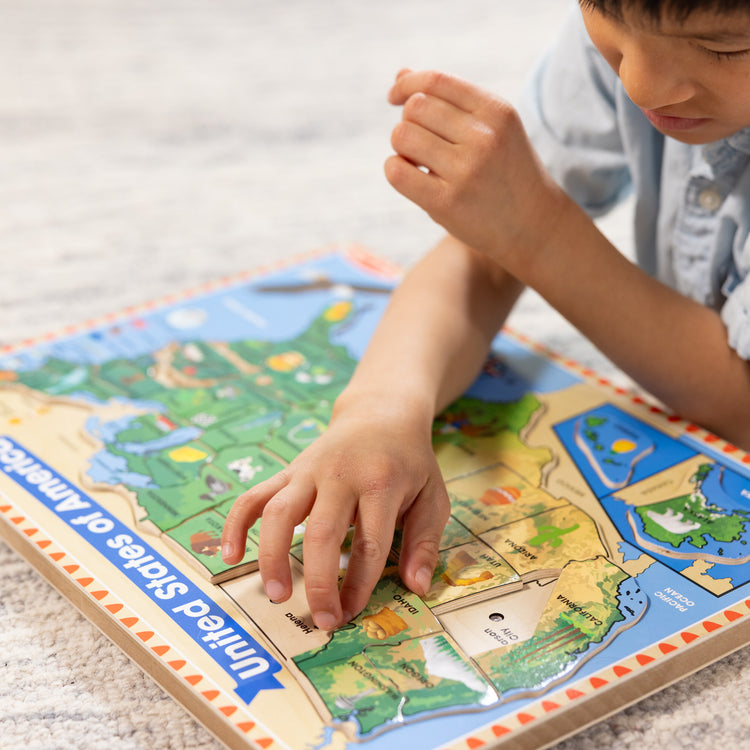 A kid playing with The Melissa & Doug USA Map Sound Puzzle - Wooden Puzzle With Sound Effects (40 pcs), Multicolor