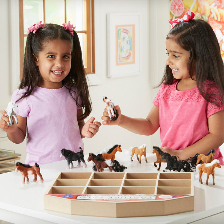 A kid playing with The Melissa & Doug Pasture Pals - 12 Collectible Horses With Wooden Barn-Shaped Crate