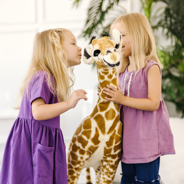 A kid playing with The Melissa & Doug Lifelike Plush Standing Baby Giraffe Stuffed Animal – 3 Feet Tall