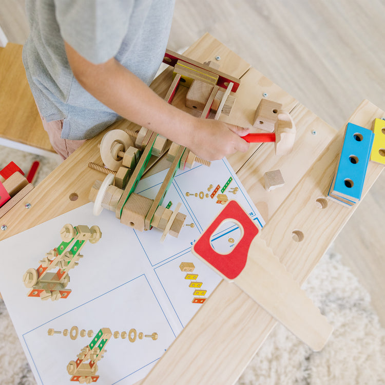 A kid playing with The Melissa & Doug Solid Wood Project Workbench Play Building Set