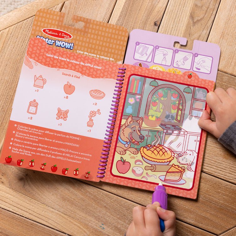 A kid playing with The Melissa & Doug Scented Water WOW! Reusable Water-Reveal Coloring Activity Pad Travel Toy – Treats