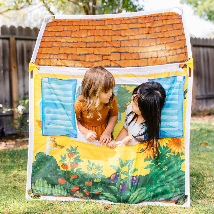 A kid playing with The Melissa & Doug Cozy Cottage Fabric Play Tent and Storage Tote